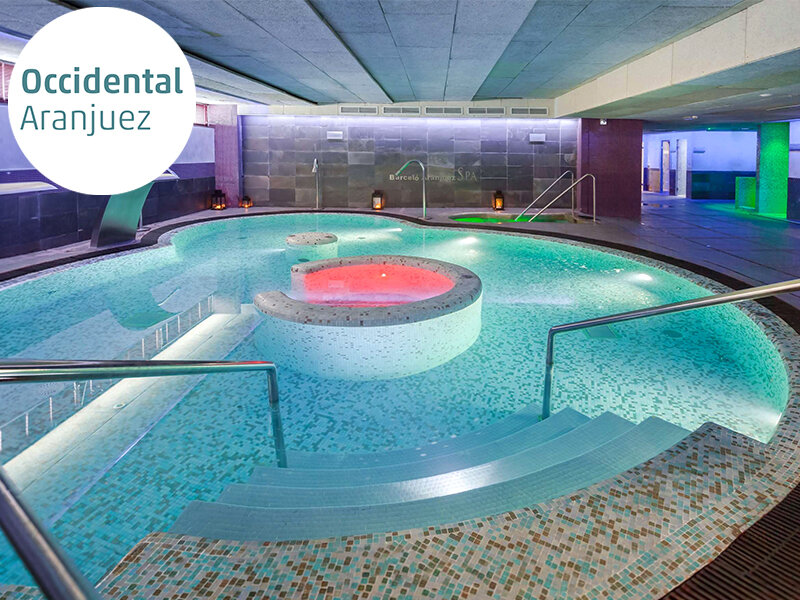 Una piscina interior moderna con azulejos de mosaico coloridos y luz roja.