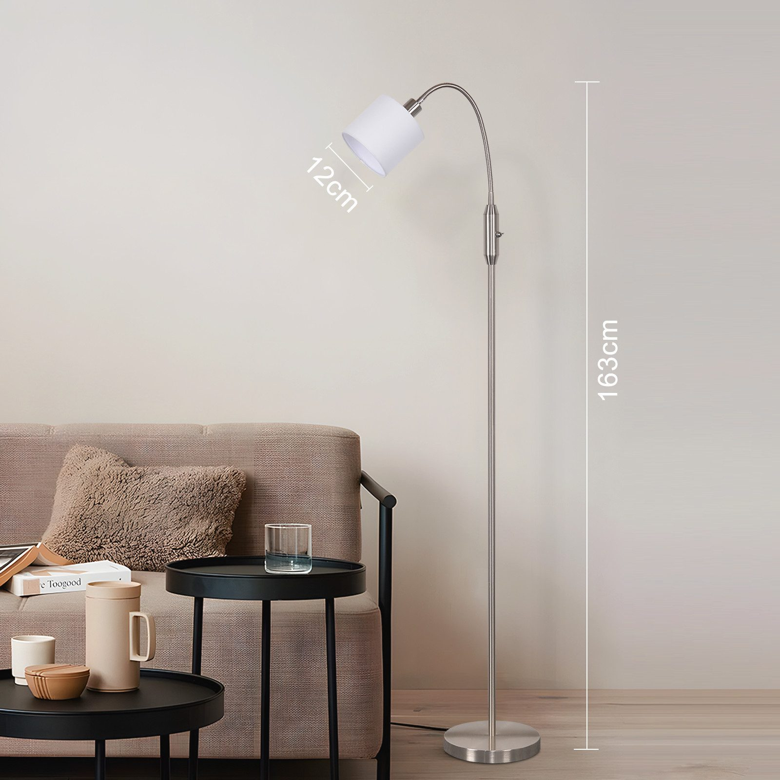 Un'elegante lampada da terra accanto a un divano con cuscini e tavolini.