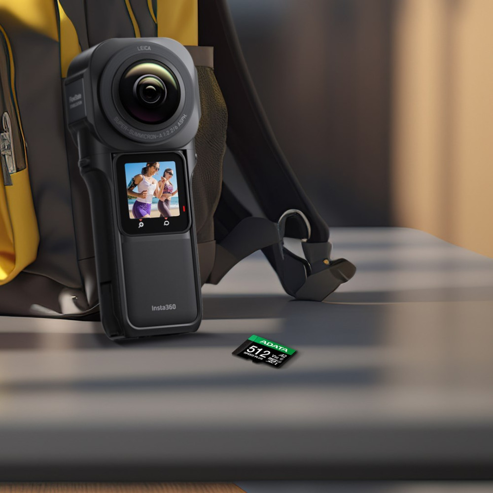 Czarna kamera Insta360 z kartą pamięci obok, przed plecakiem.