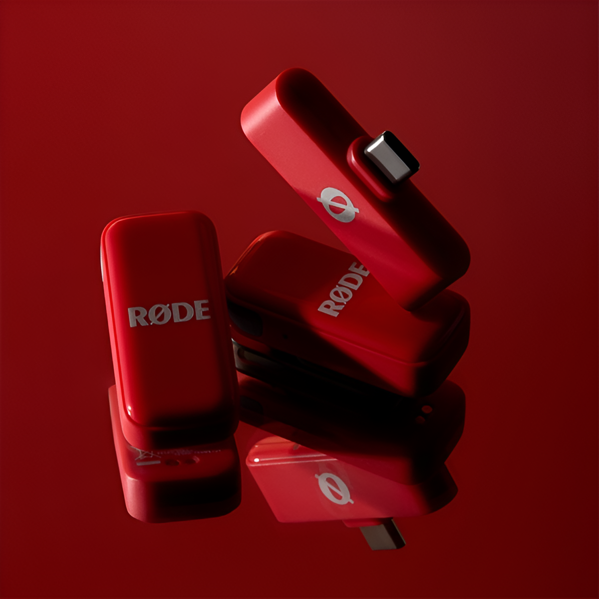 Trzy czerwone nadajniki RØDE Wireless GO II na błyszczącej czerwonej powierzchni.