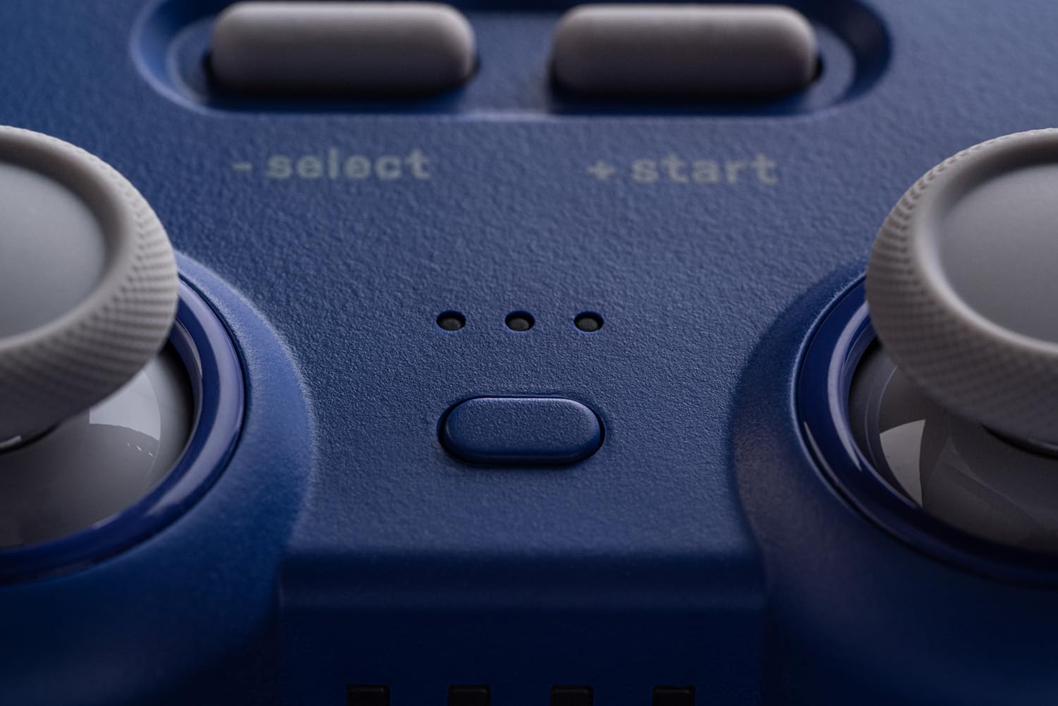 Zbliżenie niebieskiego kontrolera z przyciskami select/start i joystickami.