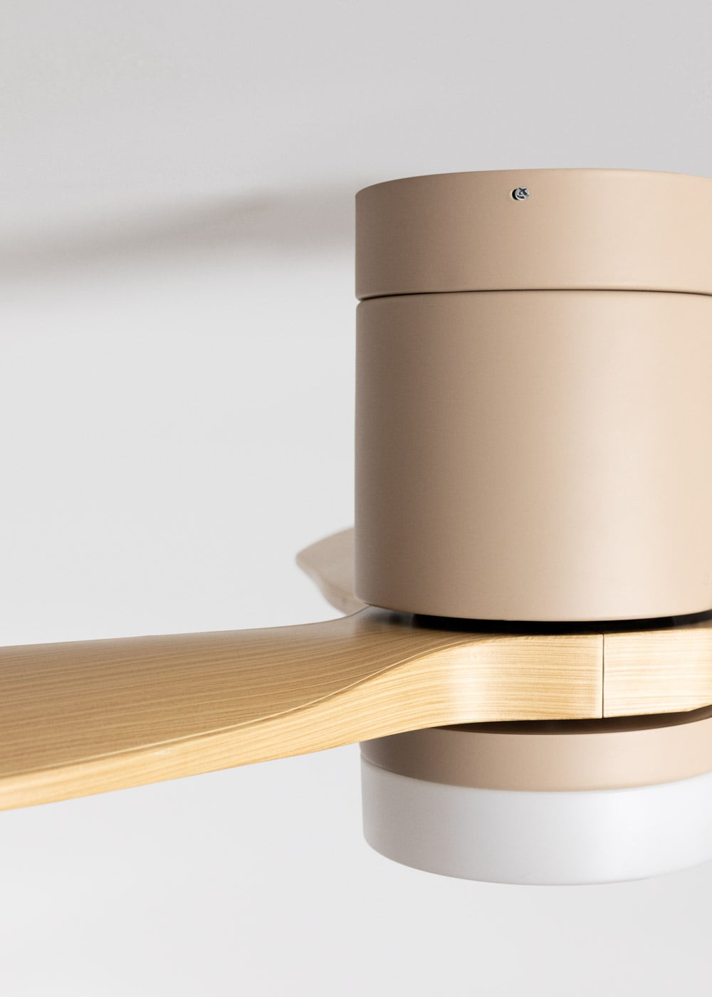 Un ventilador de techo moderno con aspa de madera y carcasa tostada.