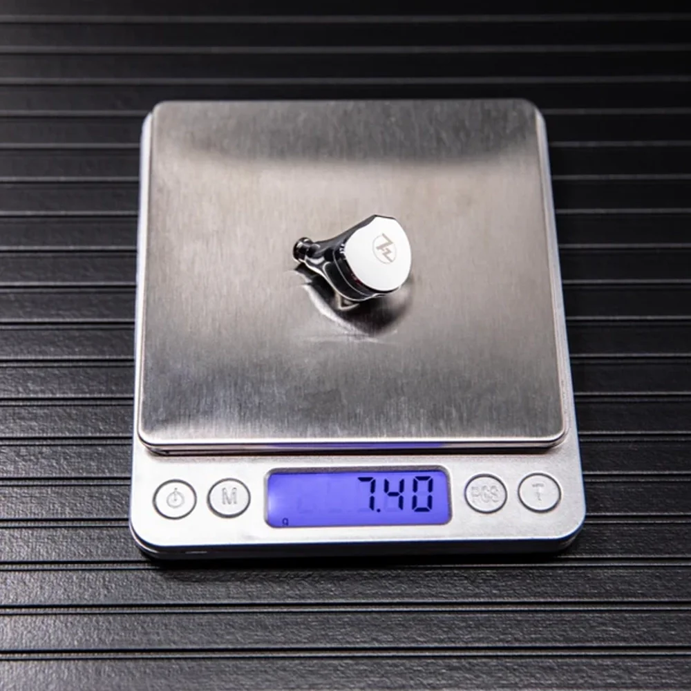 7,40 gr gösteren dijital tartıda beyaz üstlü küçük gümüş nesne.
