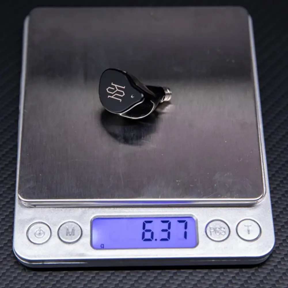 Gümüş logolu siyah kulaklık, 6,37g gösteren dijital tartıda.