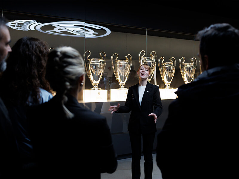 Una mujer explica trofeos a un grupo en una exposición.