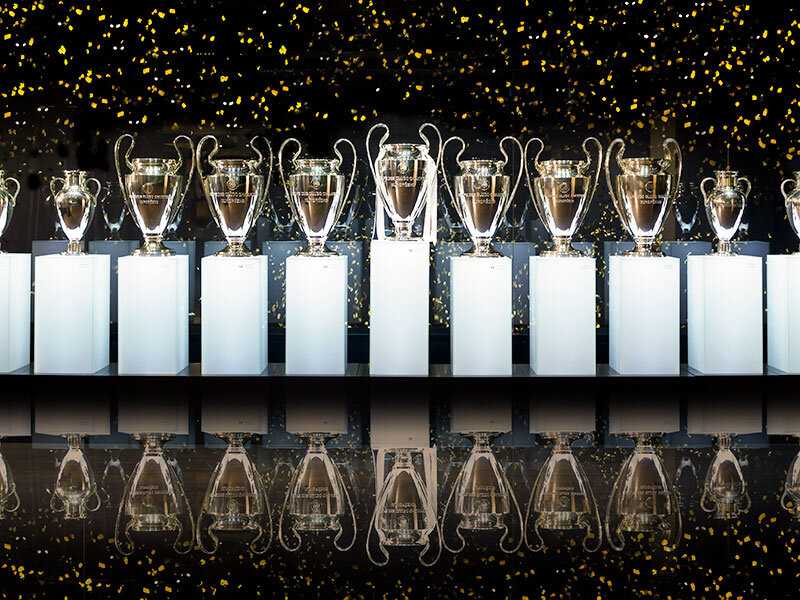 Una fila de trofeos sobre soportes blancos, con confeti esparcido.