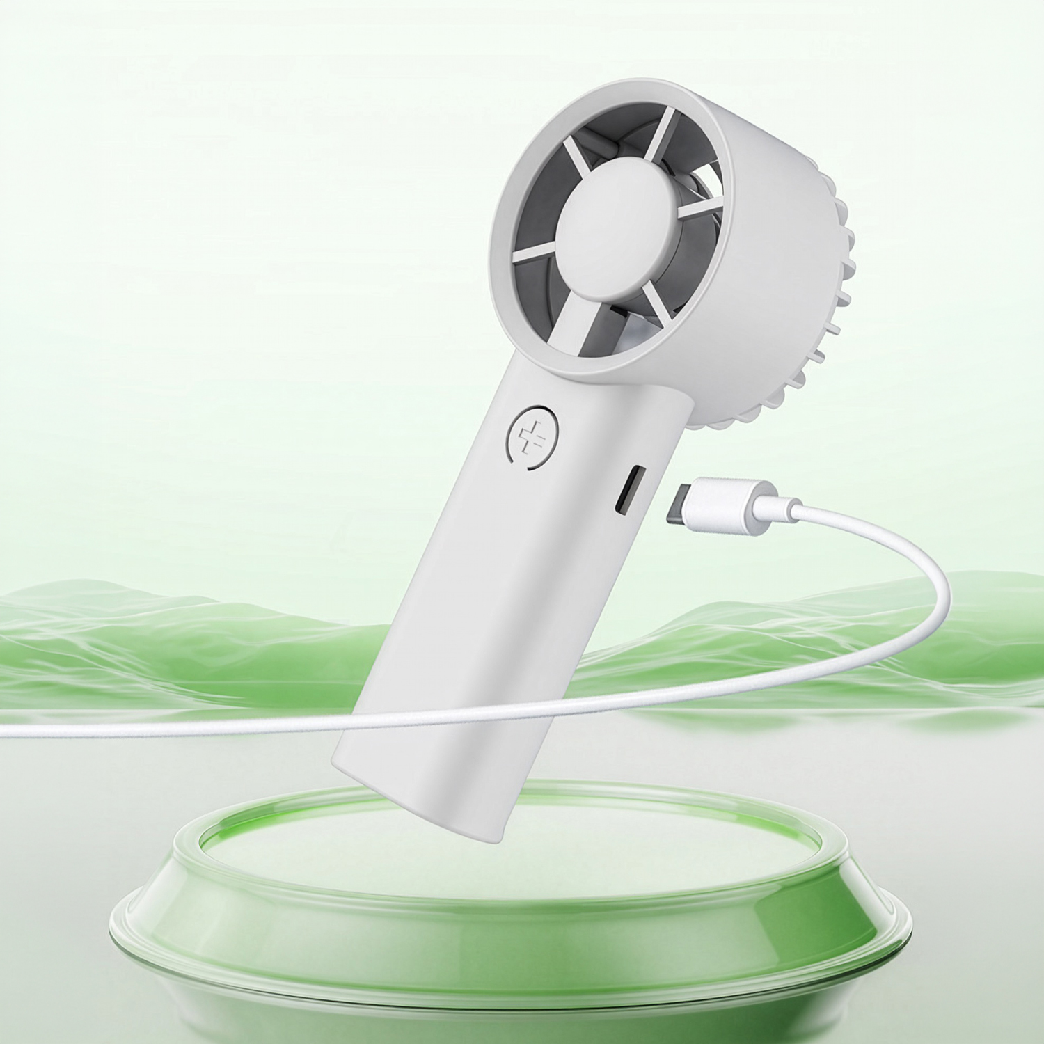 Un ventilador blanco de mano con cable USB, sobre una plataforma verde.