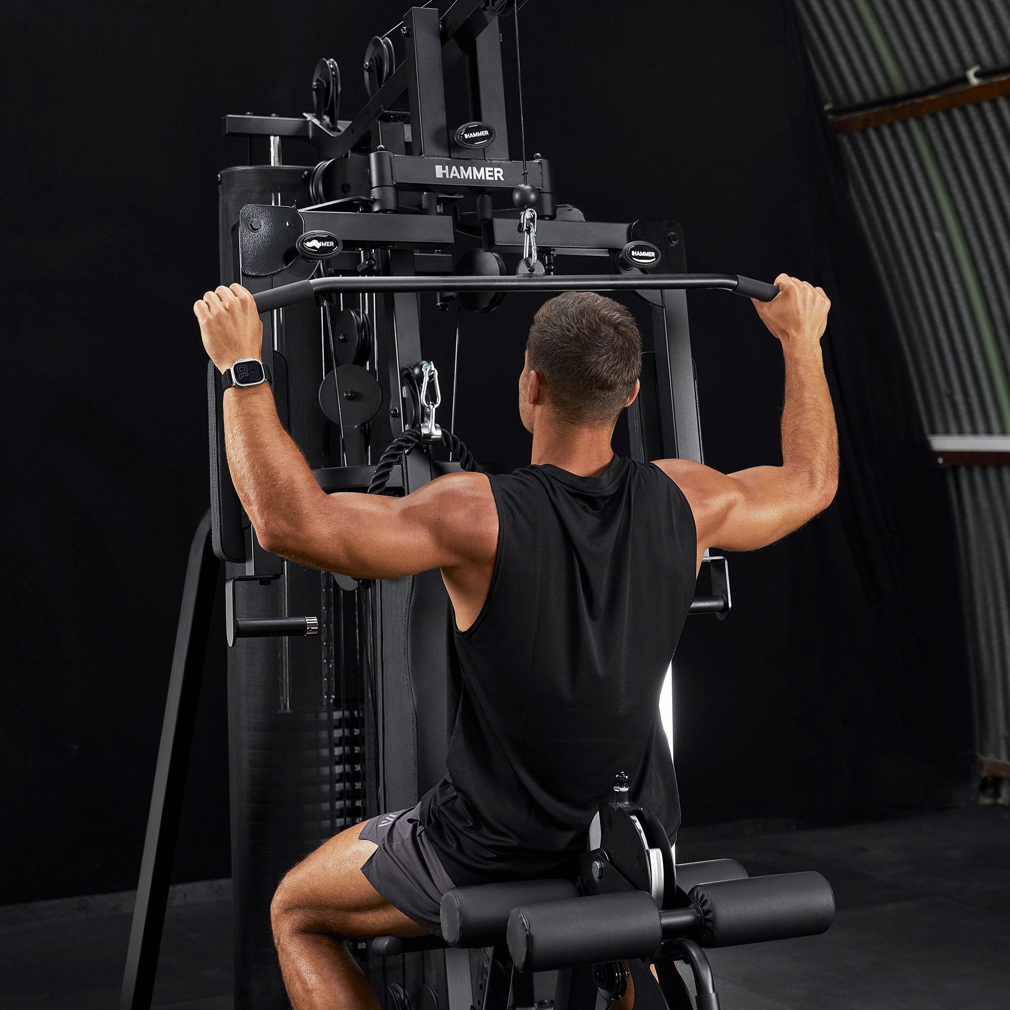 Ein Mann trainiert mit einer schwarzen Latzugmaschine in einem Fitnessstudio.