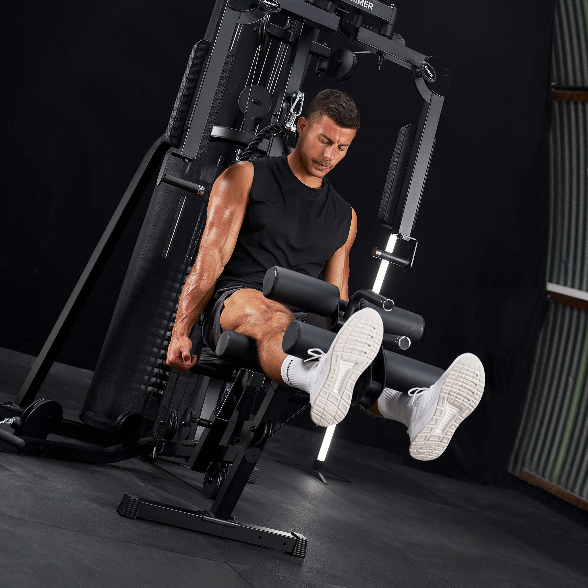 Mann auf einer Beinbeuger-Maschine im Fitnessstudio, beim Training.