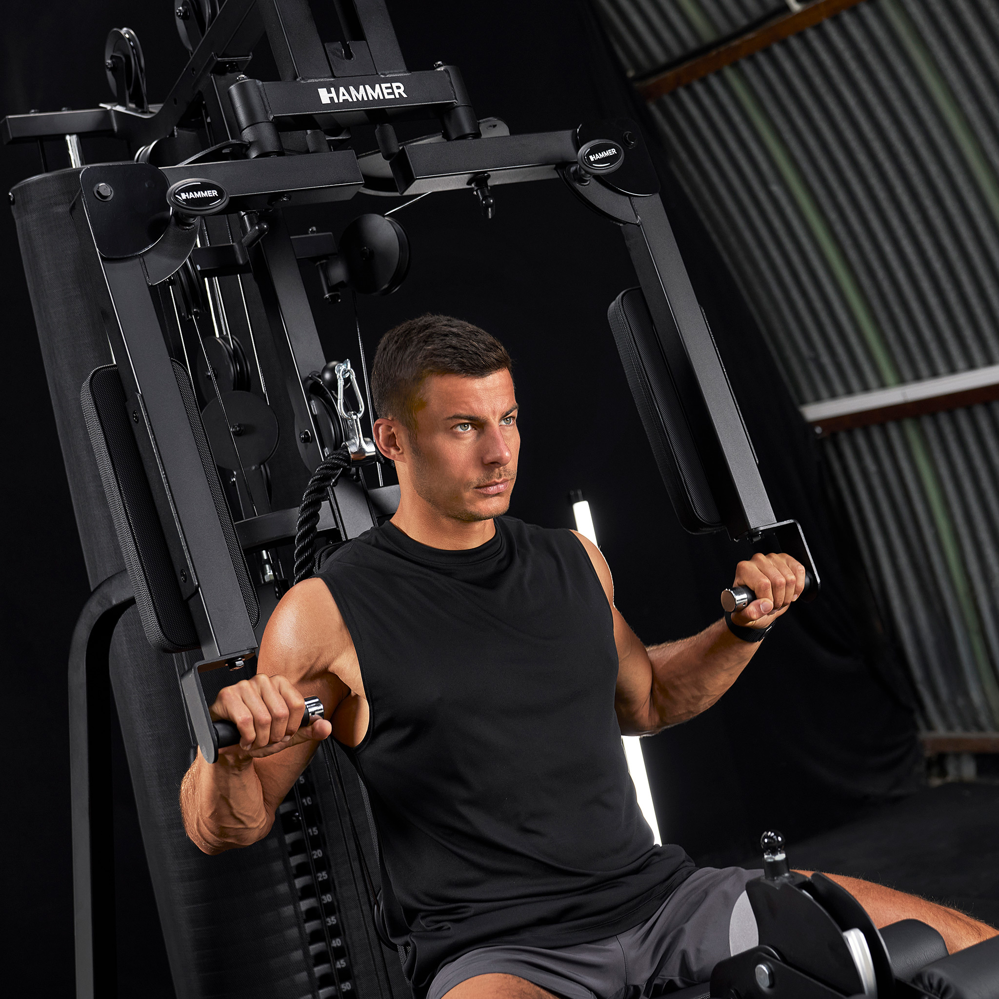 Ein Mann trainiert an einem schwarzen Fitnessgerät mit Gewichten.