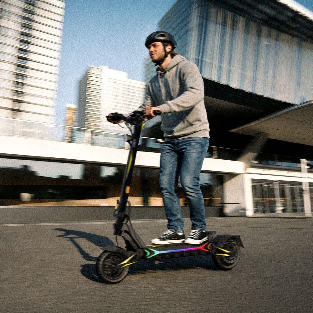Uomo guida monopattino elettrico con casco, jeans, felpa, luci colorate.