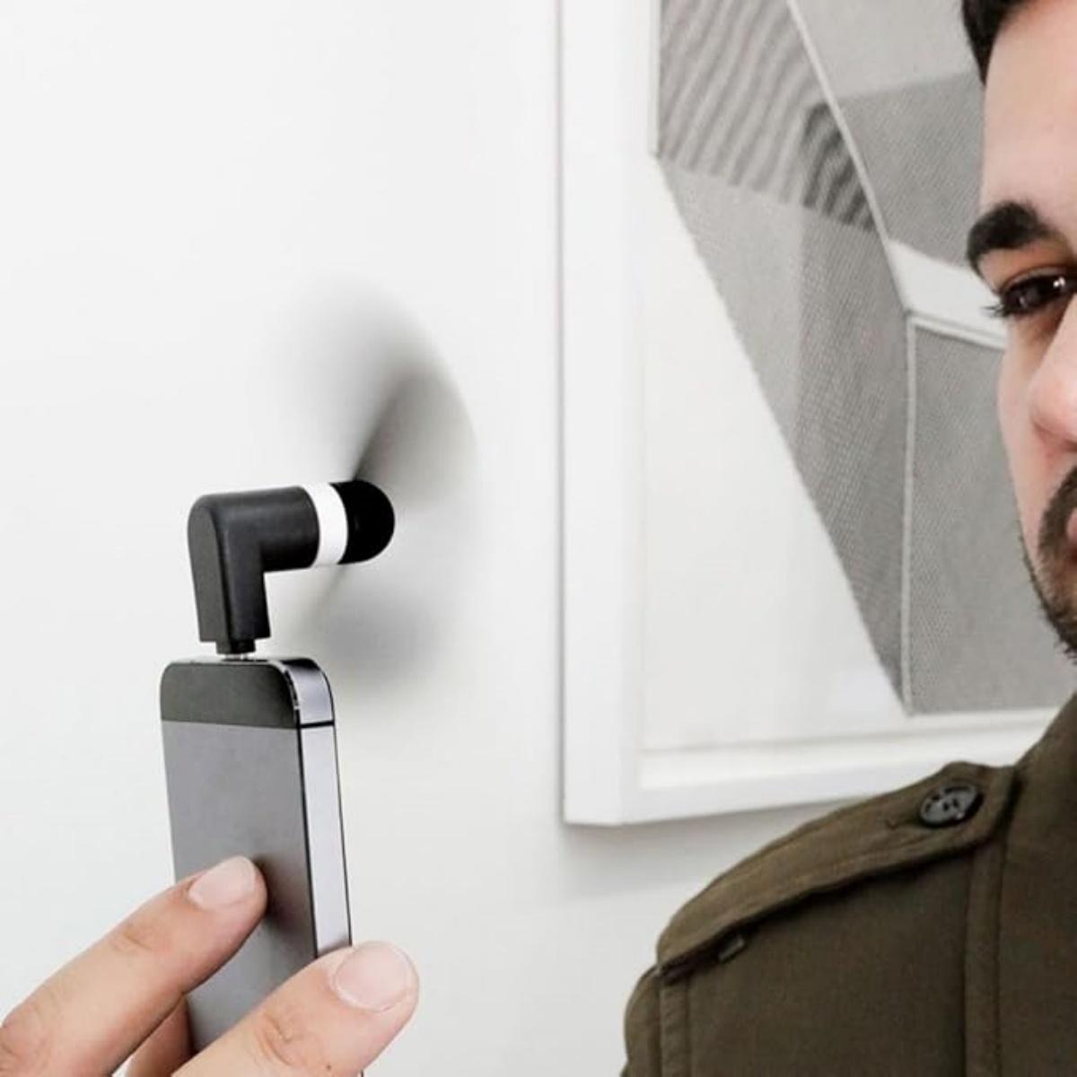 Ein Mann hält ein Smartphone mit einem kleinen Ventilator-Aufsatz, der sich dreht.