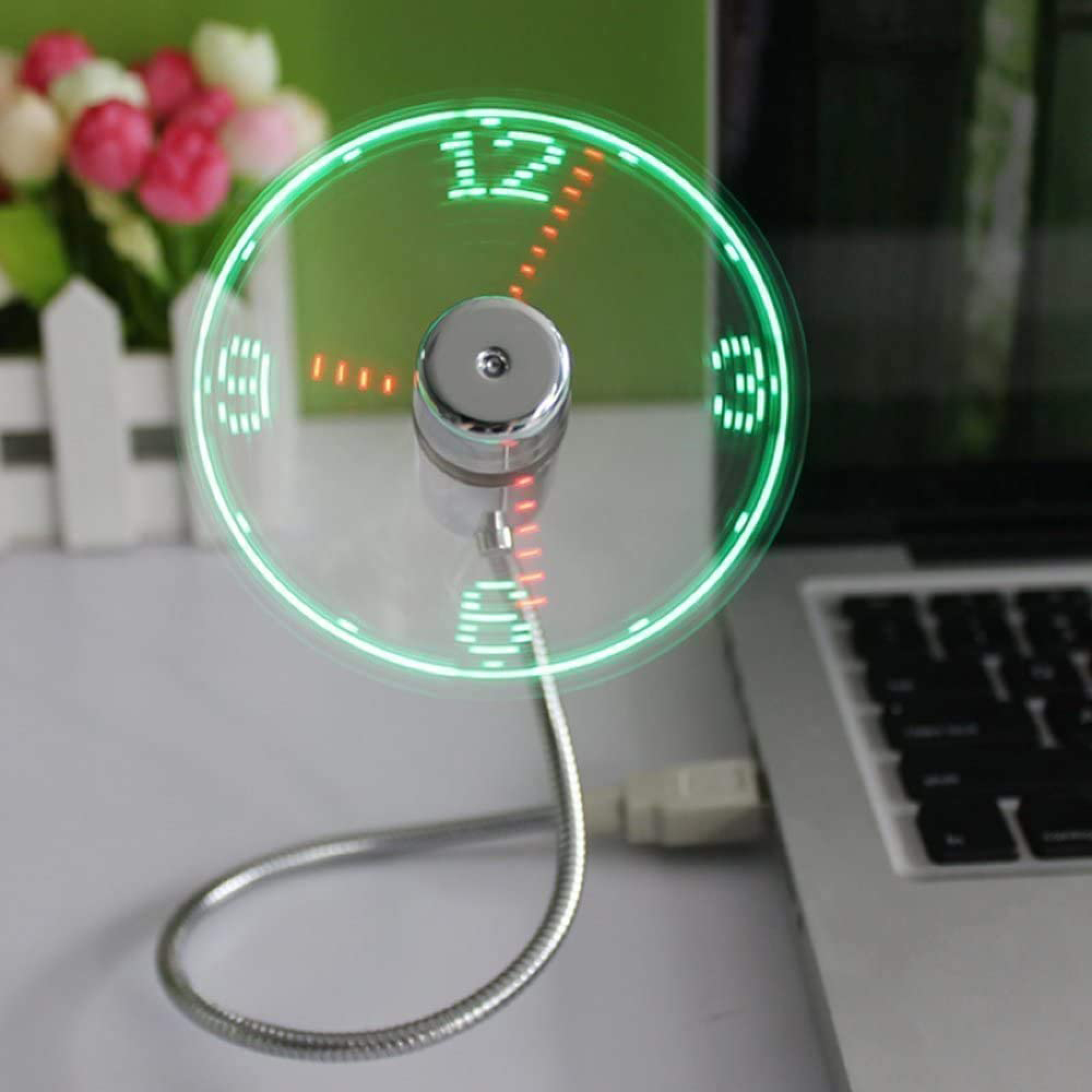 Ein kleiner USB-Ventilator mit grünen LED-Zahlen, die eine Uhrzeit anzeigen, neben einem Laptop.