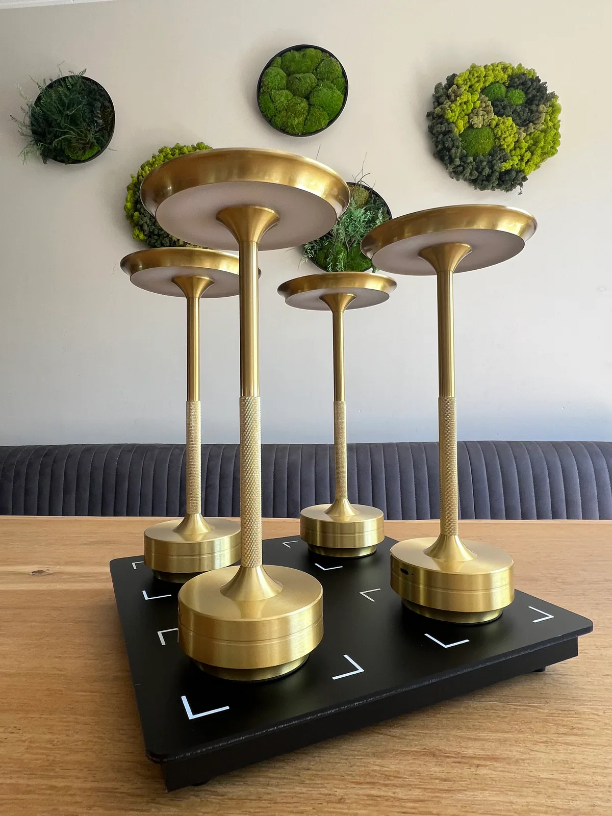 Vier goldene Lampen auf einem schwarzen Tablett auf einem Holztisch.