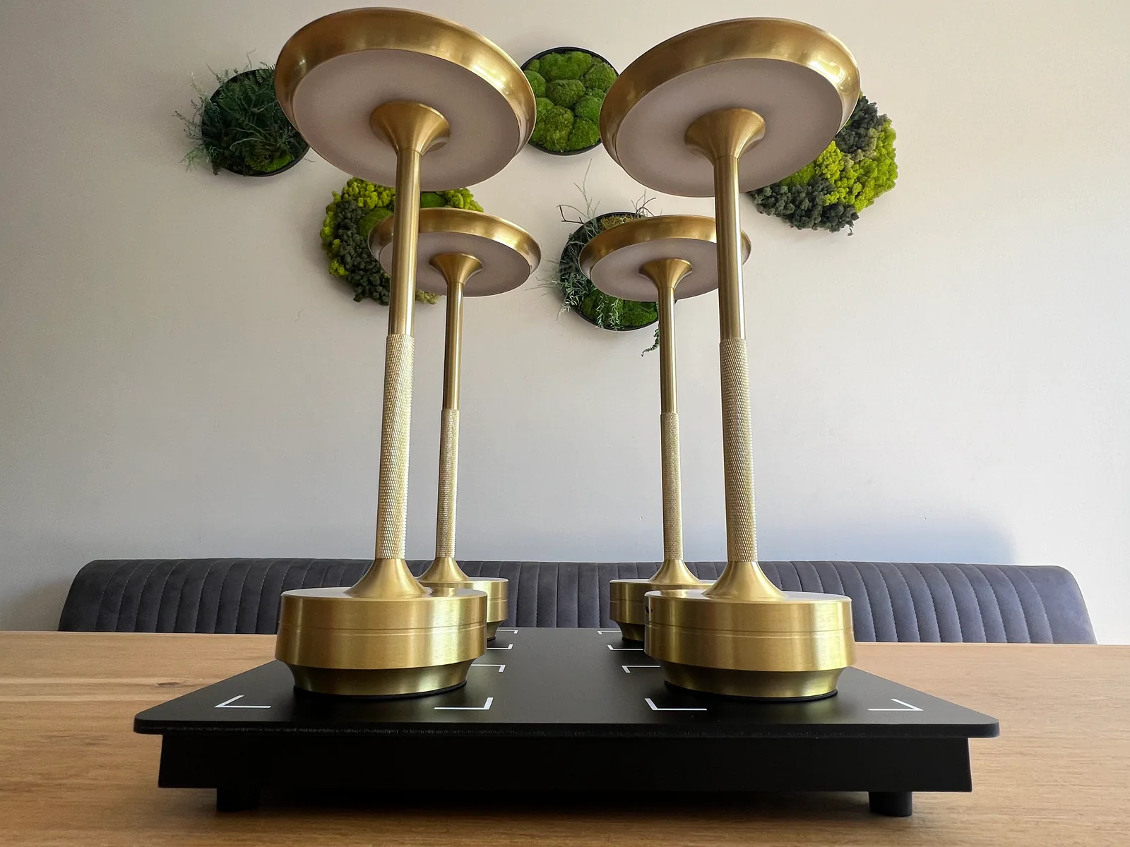 Vier goldene Lampen stehen auf einem schwarzen Sockel mit weißen Markierungen.