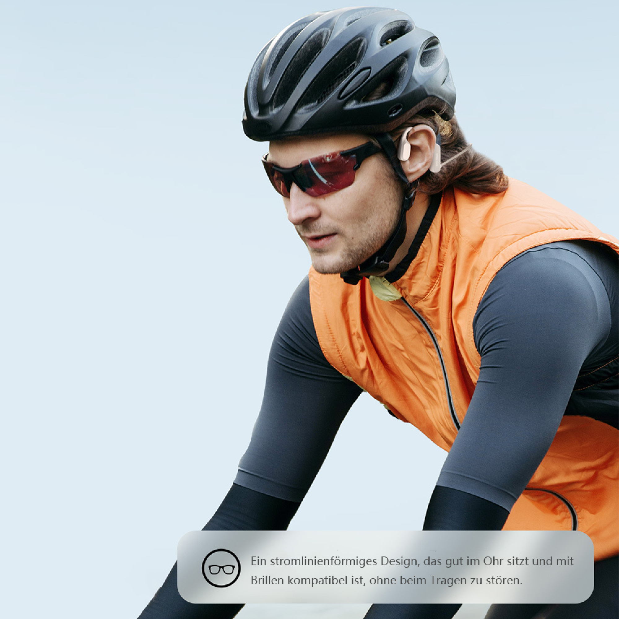 Radfahrer mit Helm, Brille und orangefarbener Weste trägt weiße Ohrhörer.