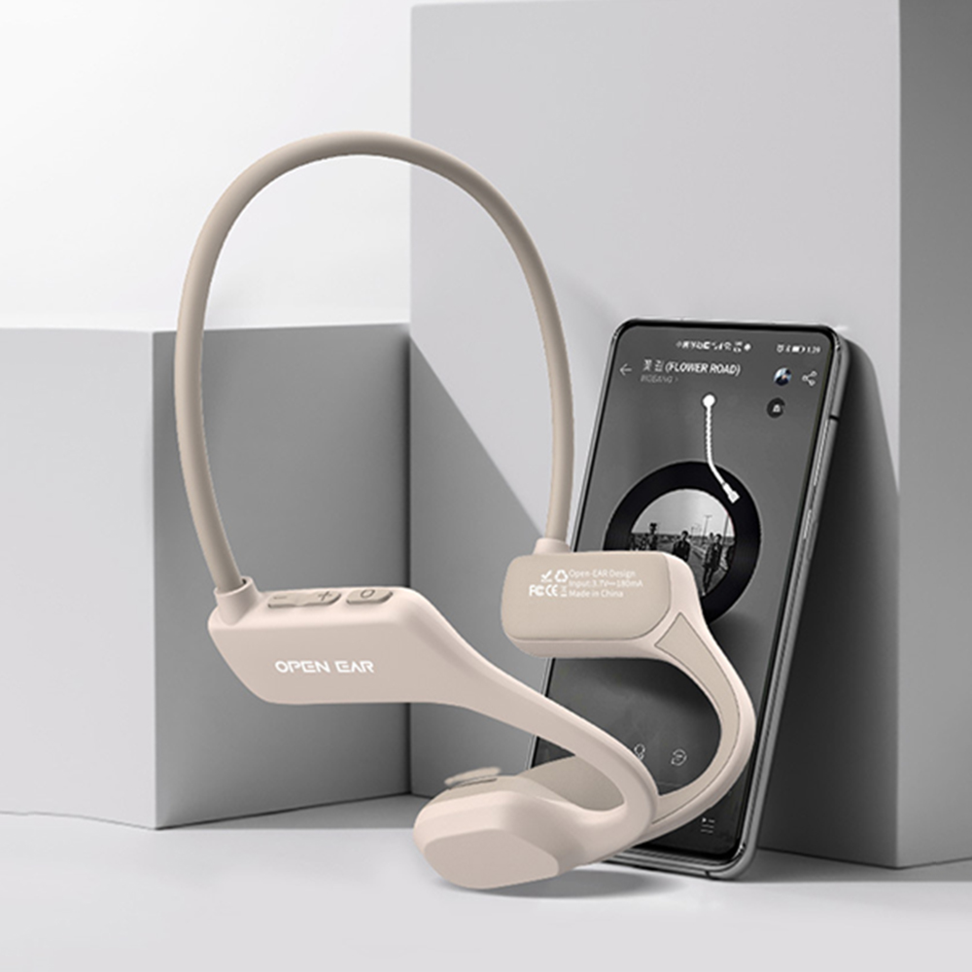 Beigefarbene Kopfhörer mit Knochenleitung liegen neben einem Smartphone, das Musik abspielt.