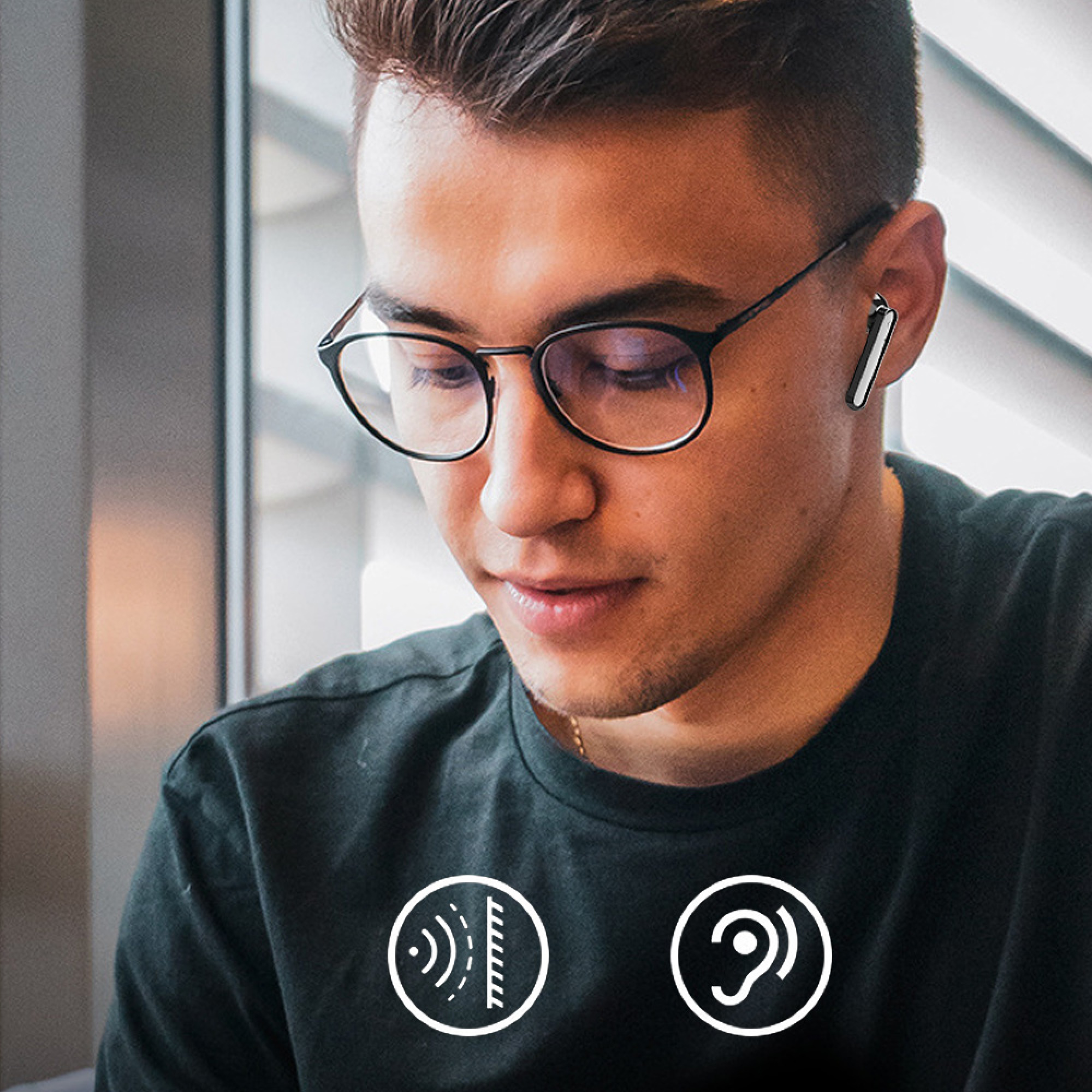 Ein Mann mit Brille trägt einen Ohrhörer und zwei weiße Symbole sind auf seinem T-Shirt.