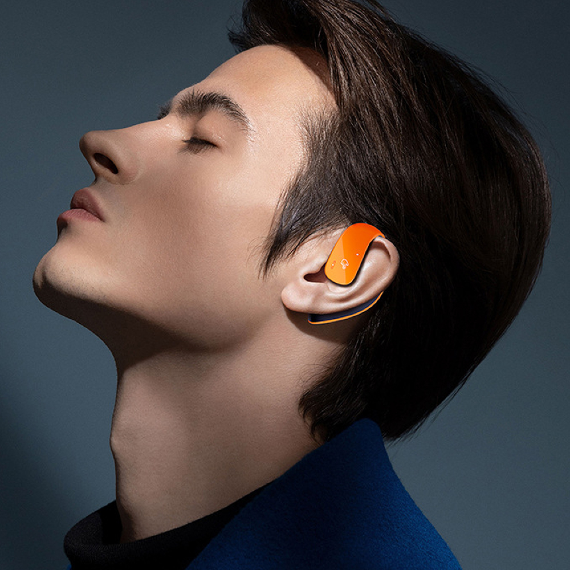 Ein Mann mit geschlossenen Augen trägt einen orangefarbenen Ohrhörer.