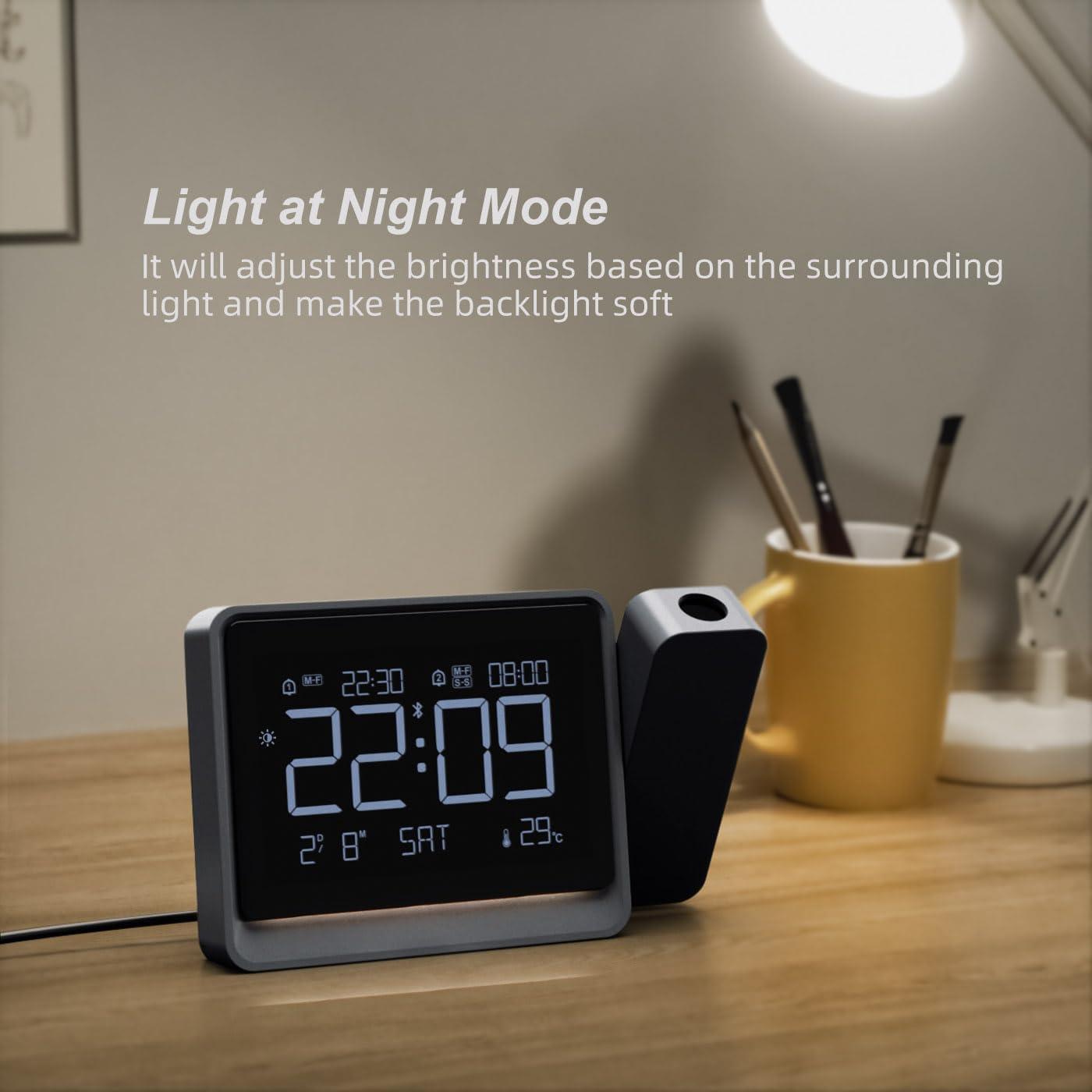 Digitaluhr mit Projektor auf Holztisch. Zeigt Zeit 22:09, Datum SA, Temp 29C.
