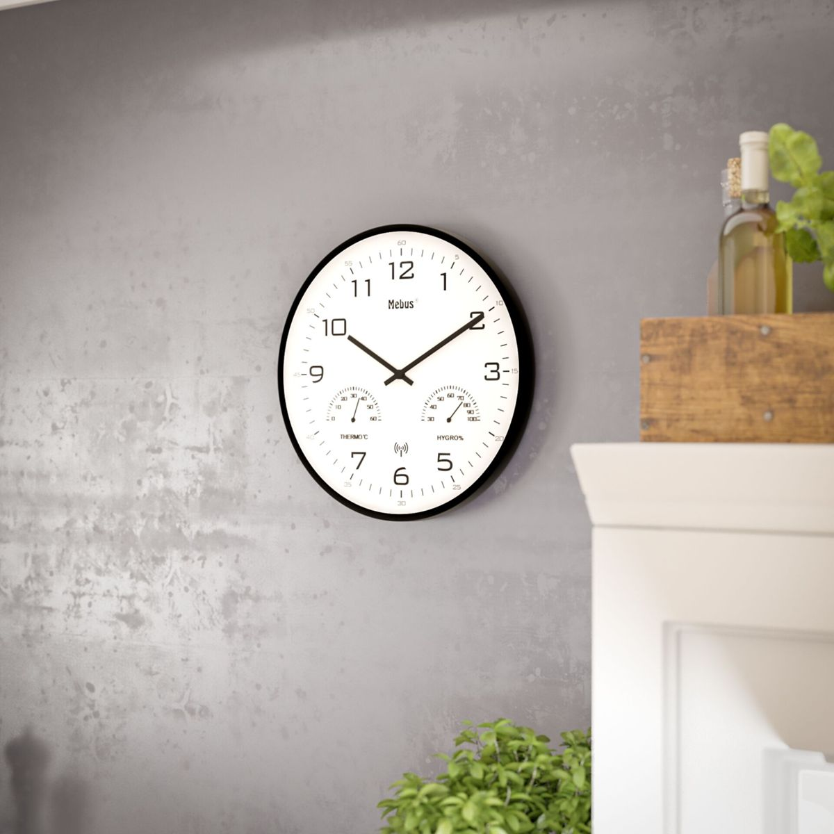 Eine weiße Wanduhr mit Thermometer und Hygrometer hängt an einer grauen Wand.