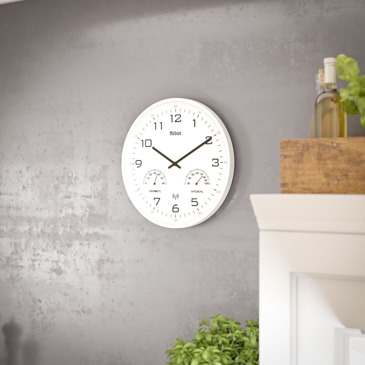 Eine weiße Wanduhr mit Thermometer und Hygrometer an einer grauen Wand.