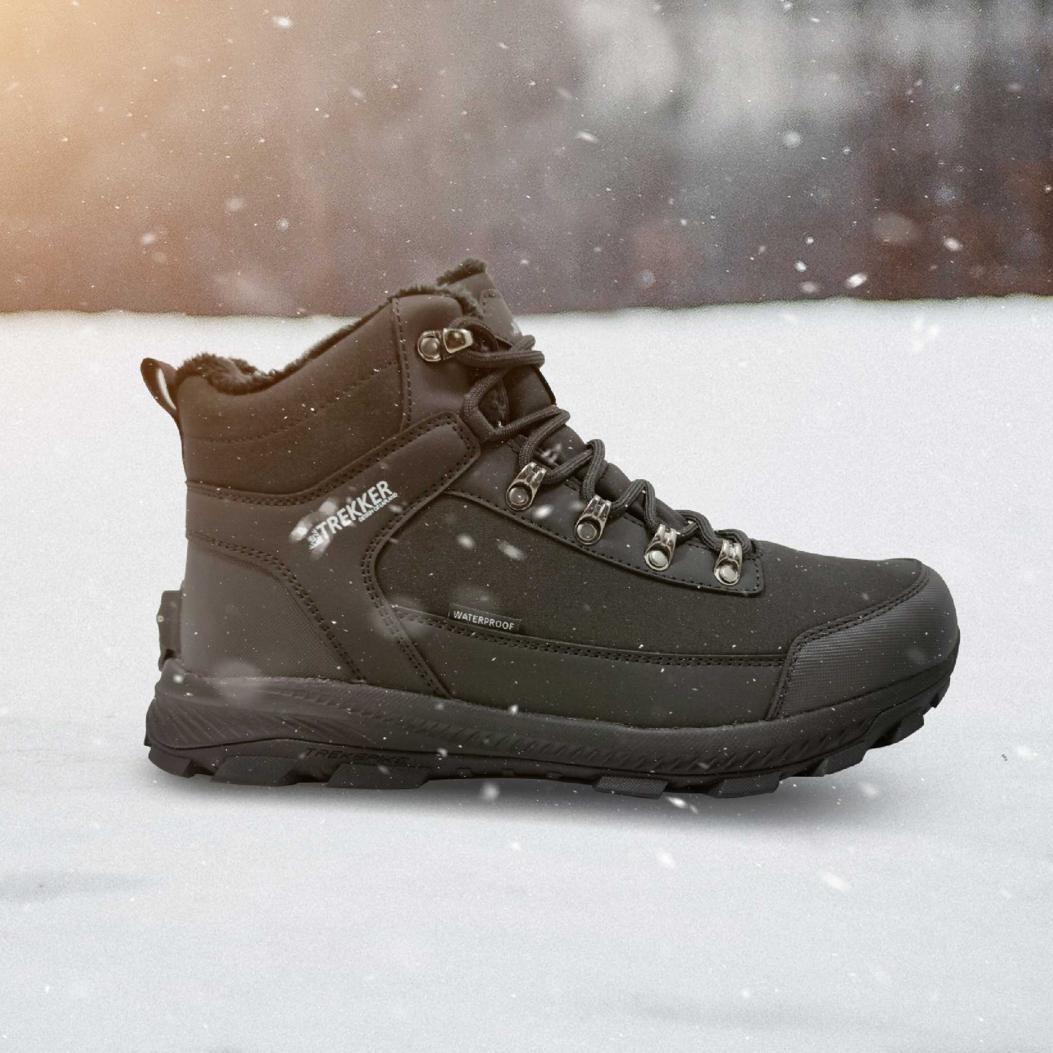 Schwarzer Winterstiefel mit Schnürsenkeln auf Schnee. Marke 'TREKKER'.