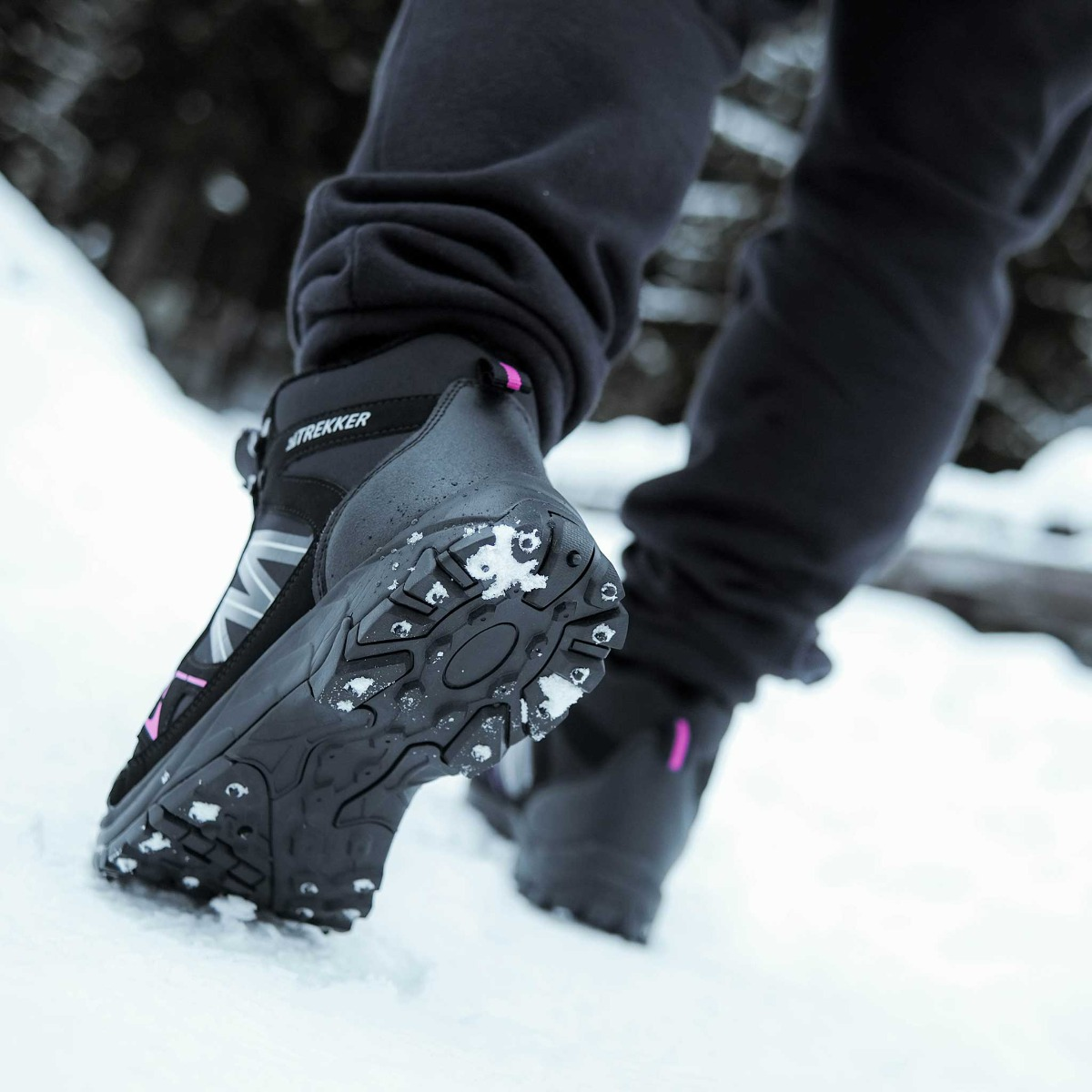 Füße in Wanderschuhen mit Schnee auf der Sohle gehen durch Schnee.