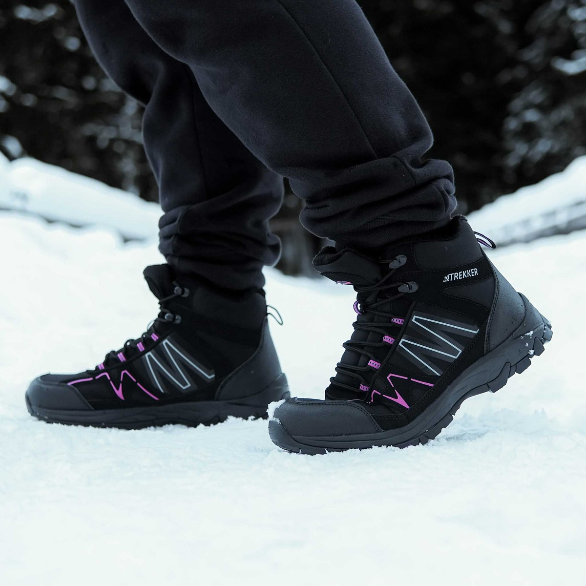 Schwarze Wanderschuhe mit pinken Akzenten auf Schnee.