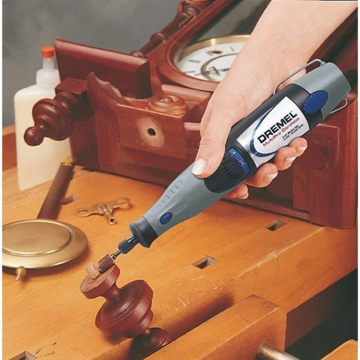 Eine Hand hält ein Dremel-Werkzeug, das an einem Holzobjekt arbeitet.