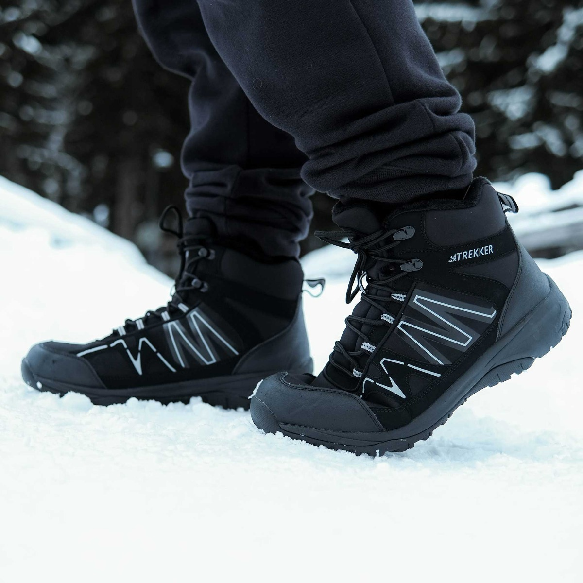 Schwarze Winterstiefel mit weißen Akzenten stehen im Schnee.