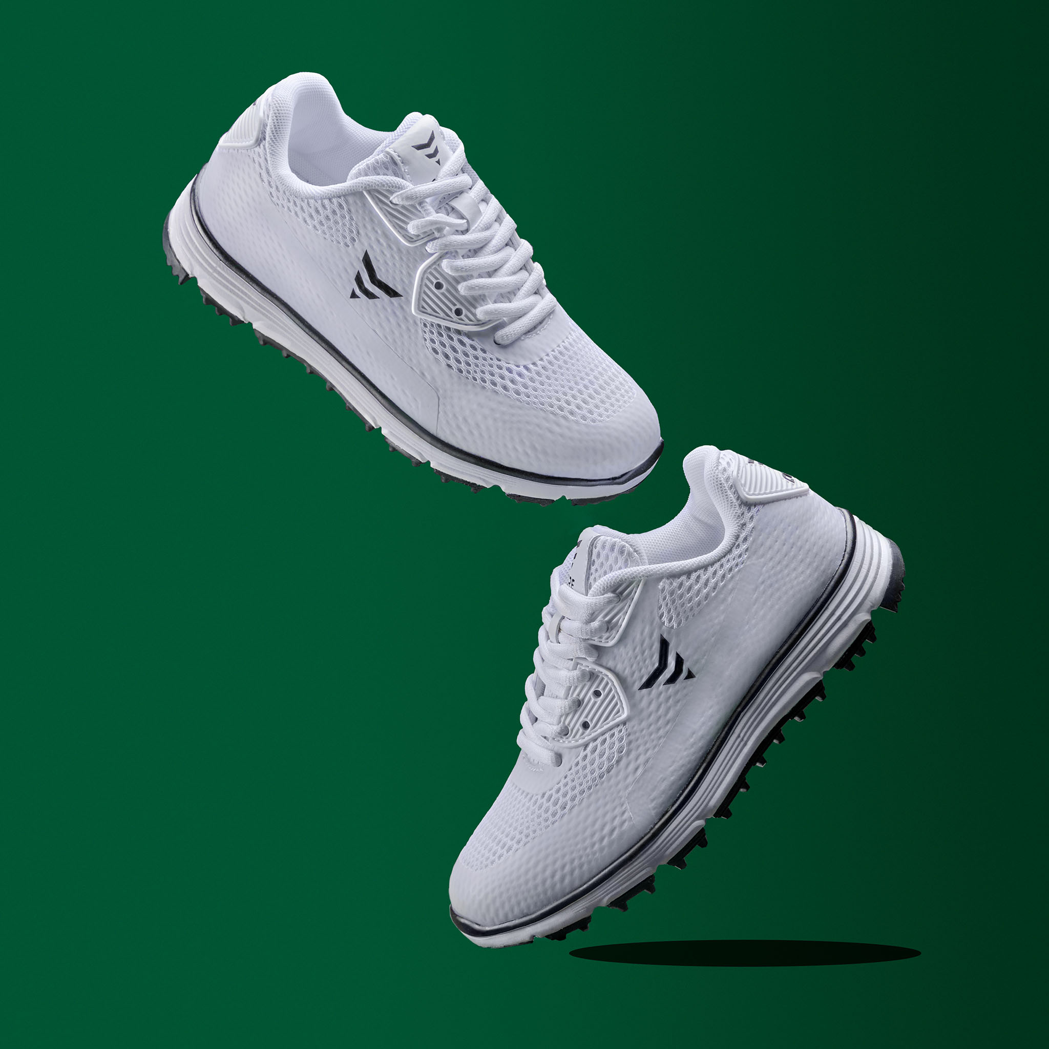 Zwei weiße Golfschuhe mit schwarzen Akzenten schweben vor einem grünen Hintergrund.