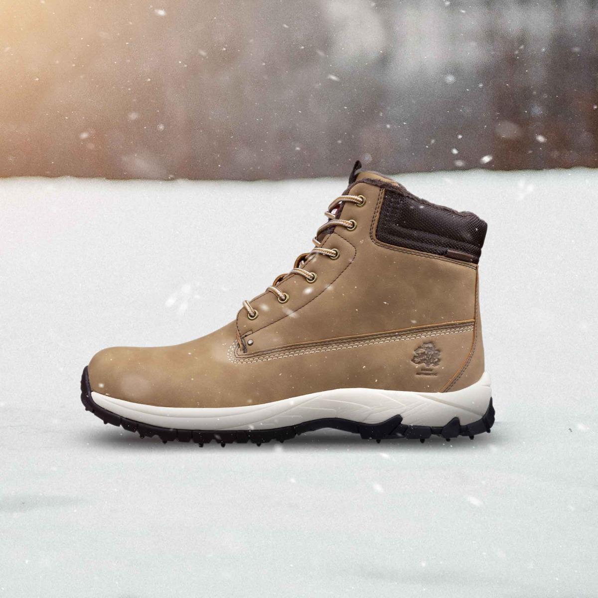 Ein tanfarbener Winterstiefel mit weißen Schnürsenkeln auf Schnee. Schnee fällt.