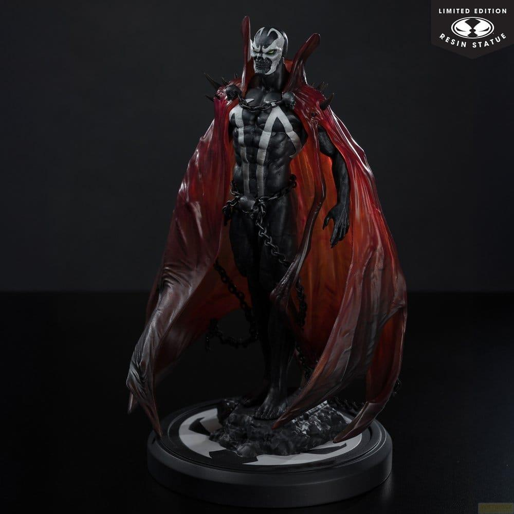 Statua di Spawn con mantello rosso, catene e simbolo bianco sul petto su sfondo scuro.