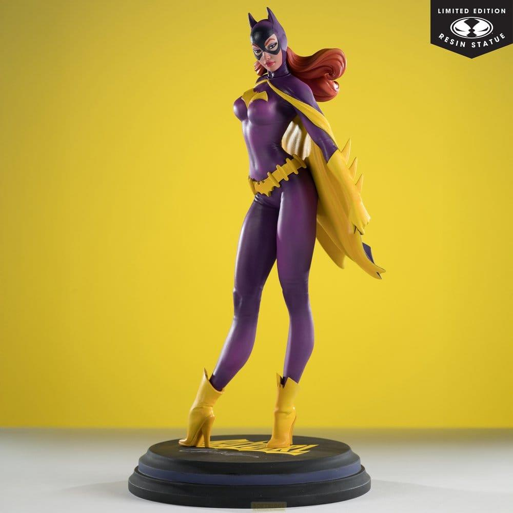 Statua viola di Batgirl con mantello e stivali gialli su base nera, sfondo giallo.