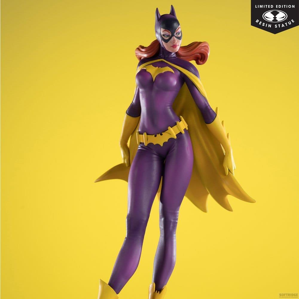 Una statua viola di Batgirl con mantello e cintura gialli su sfondo giallo.