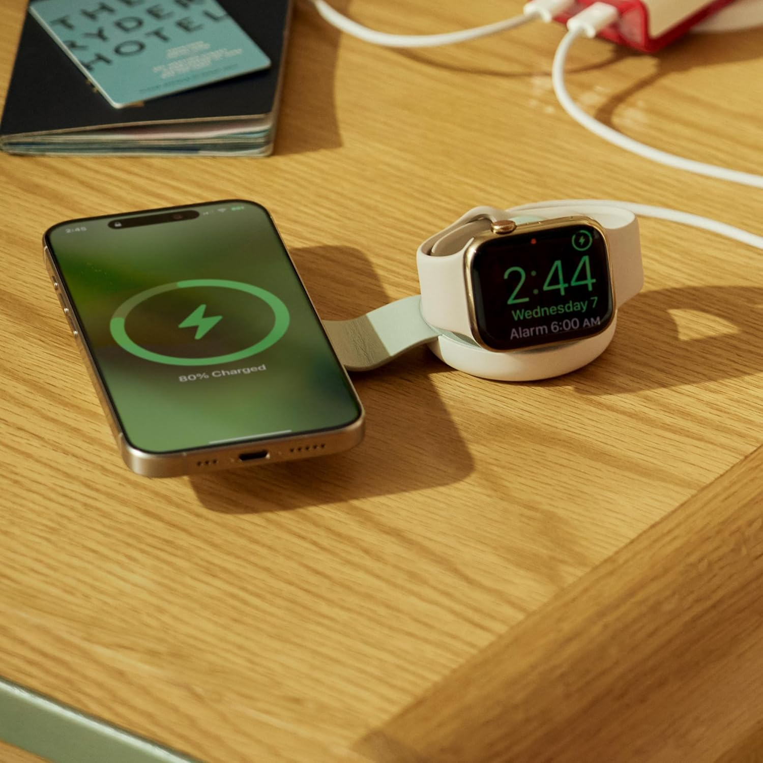 Un iPhone y un Apple Watch cargando sobre una mesa de madera.
