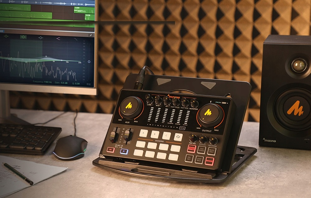 Ein Audio-Interface mit Mischpult, Monitor und Tastatur auf einem Schreibtisch.