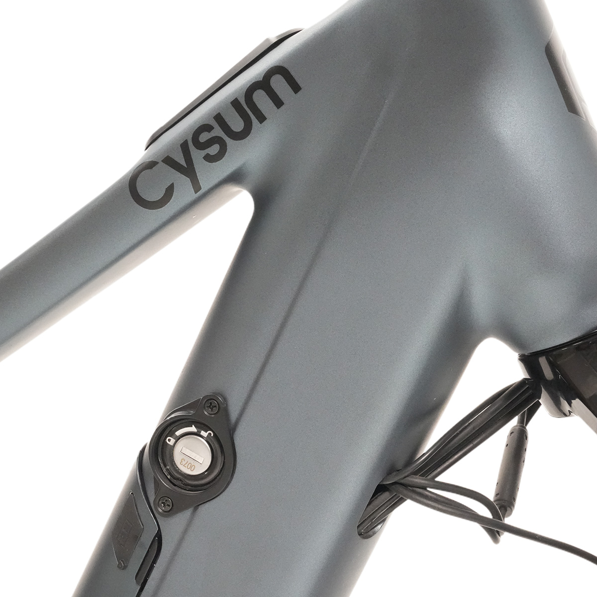 Nahaufnahme eines grauen Fahrradrahmens mit 'Cysum'-Logo, einem Schlossmechanismus und Verkabelung.