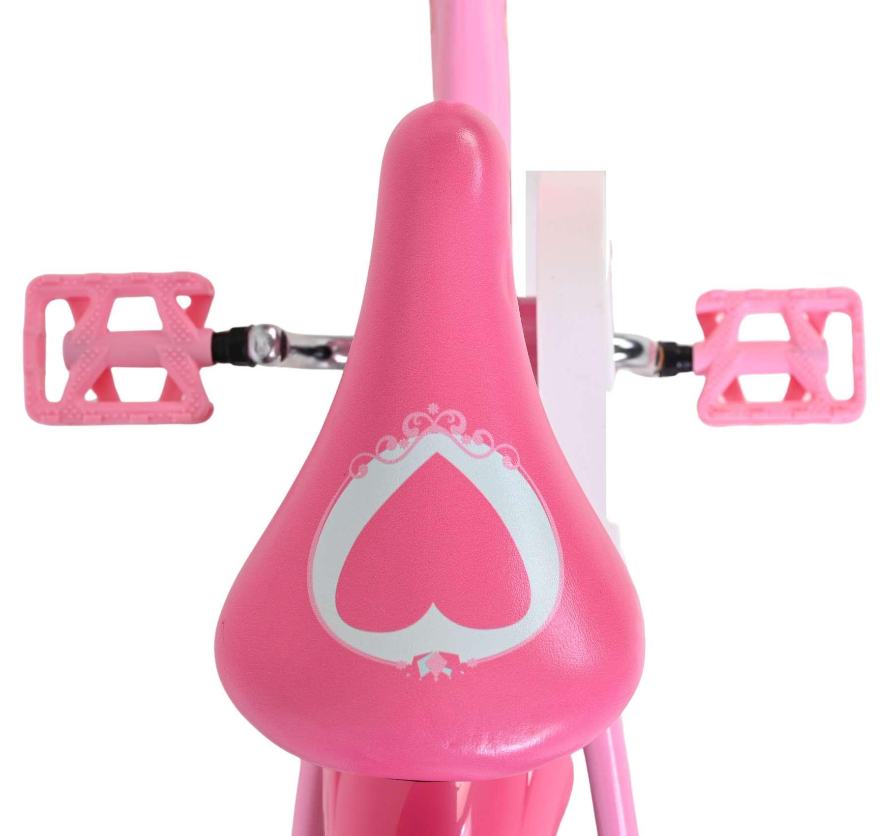 Nahaufnahme eines rosa Fahrradsattels mit Herzmotiv und Pedalen.