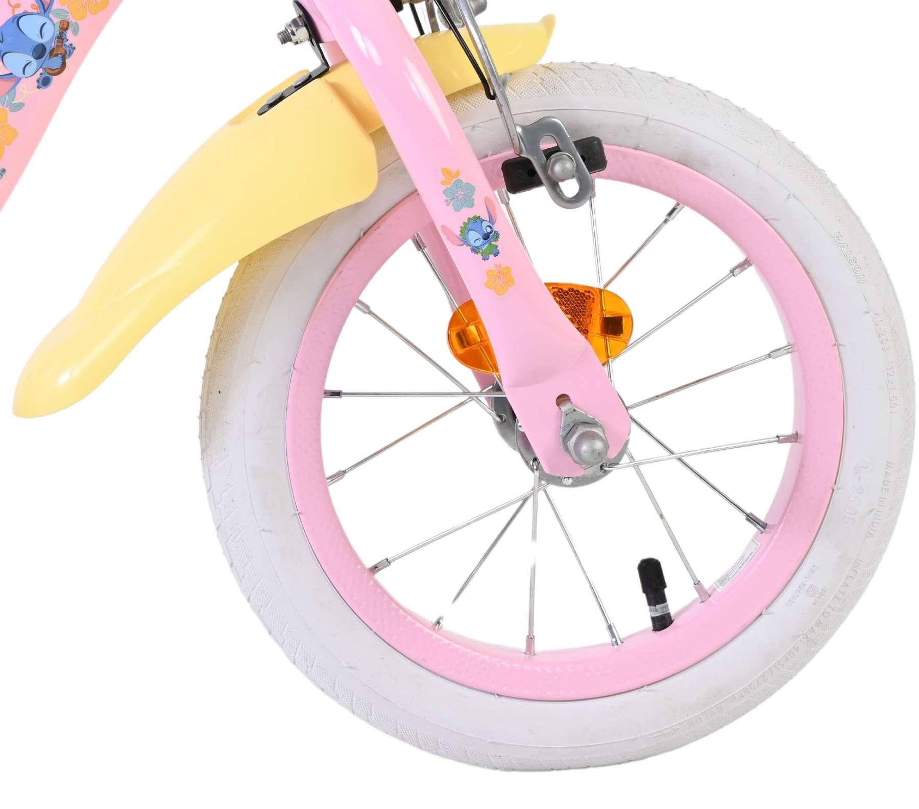 Nahaufnahme eines rosa Kinderfahrradrads mit weißem Reifen, gelbem Schutzblech und Stitch-Aufkleber.