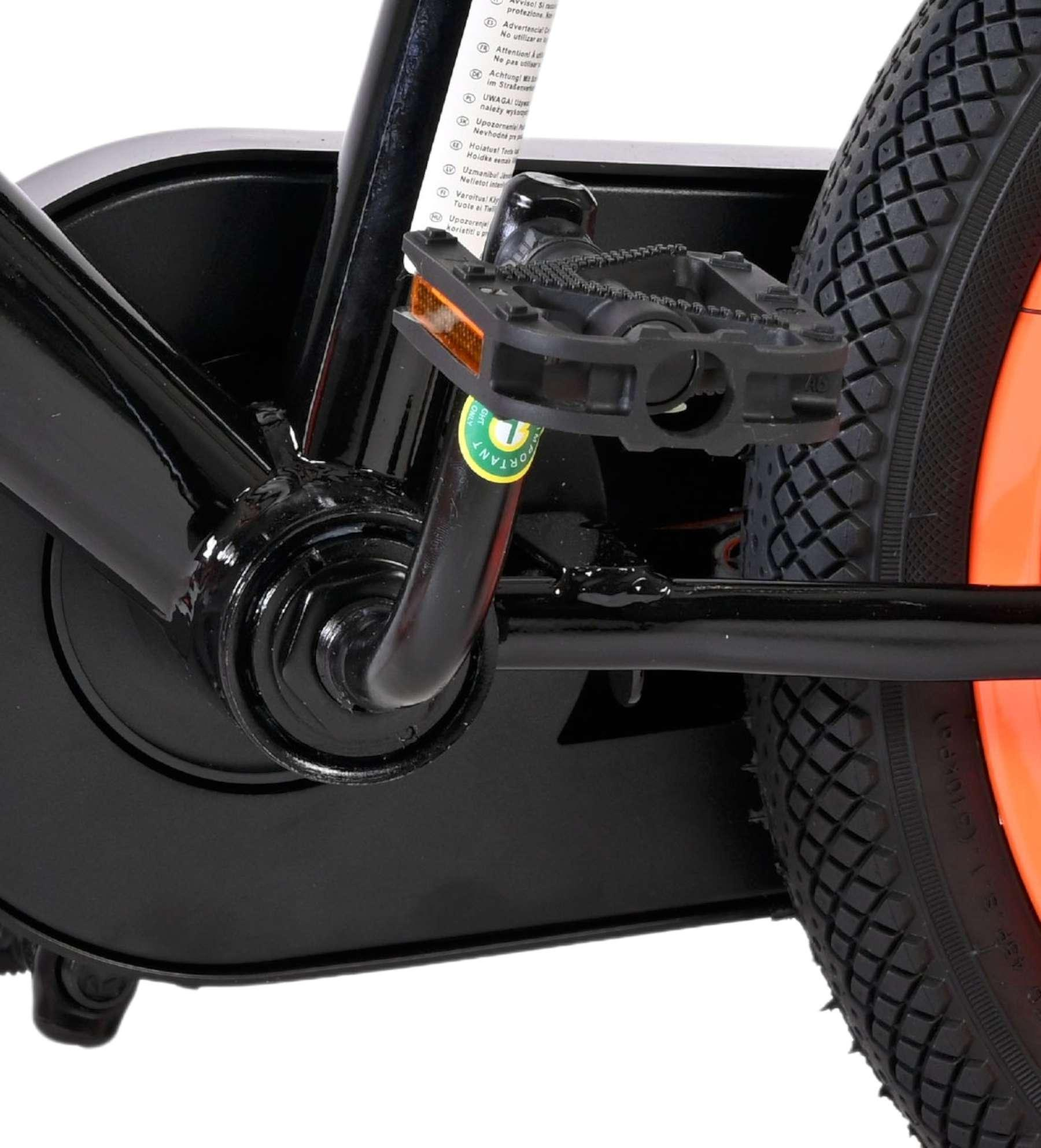 Nahaufnahme eines Fahrradpedals und Rades mit orangefarbener Felge und schwarzem Reifen.