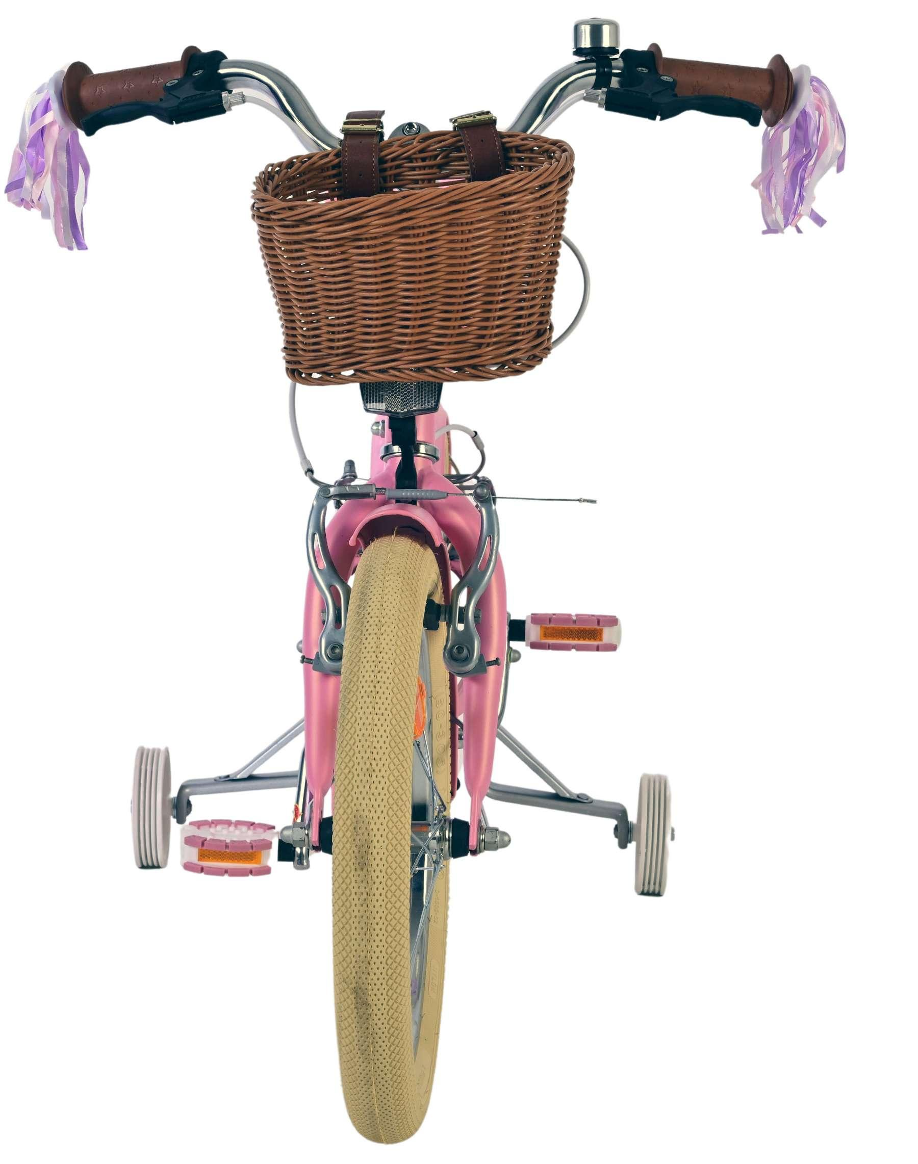 Ein rosafarbenes Kinderfahrrad mit Stützrädern, einem geflochtenen Korb und Lenkerbändern.