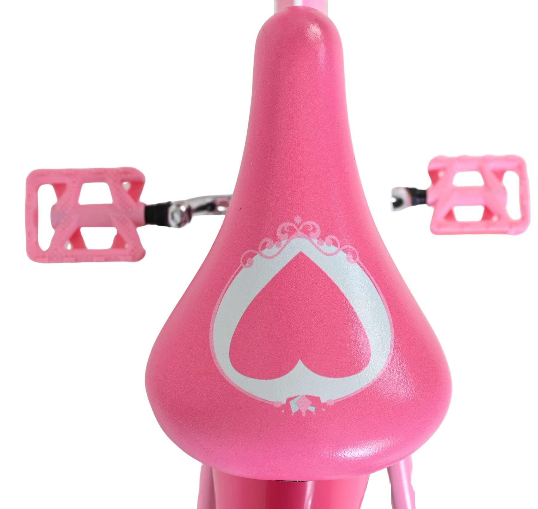 Ein rosa Fahrradsattel mit einem Herzmotiv und zwei rosa Pedalen.