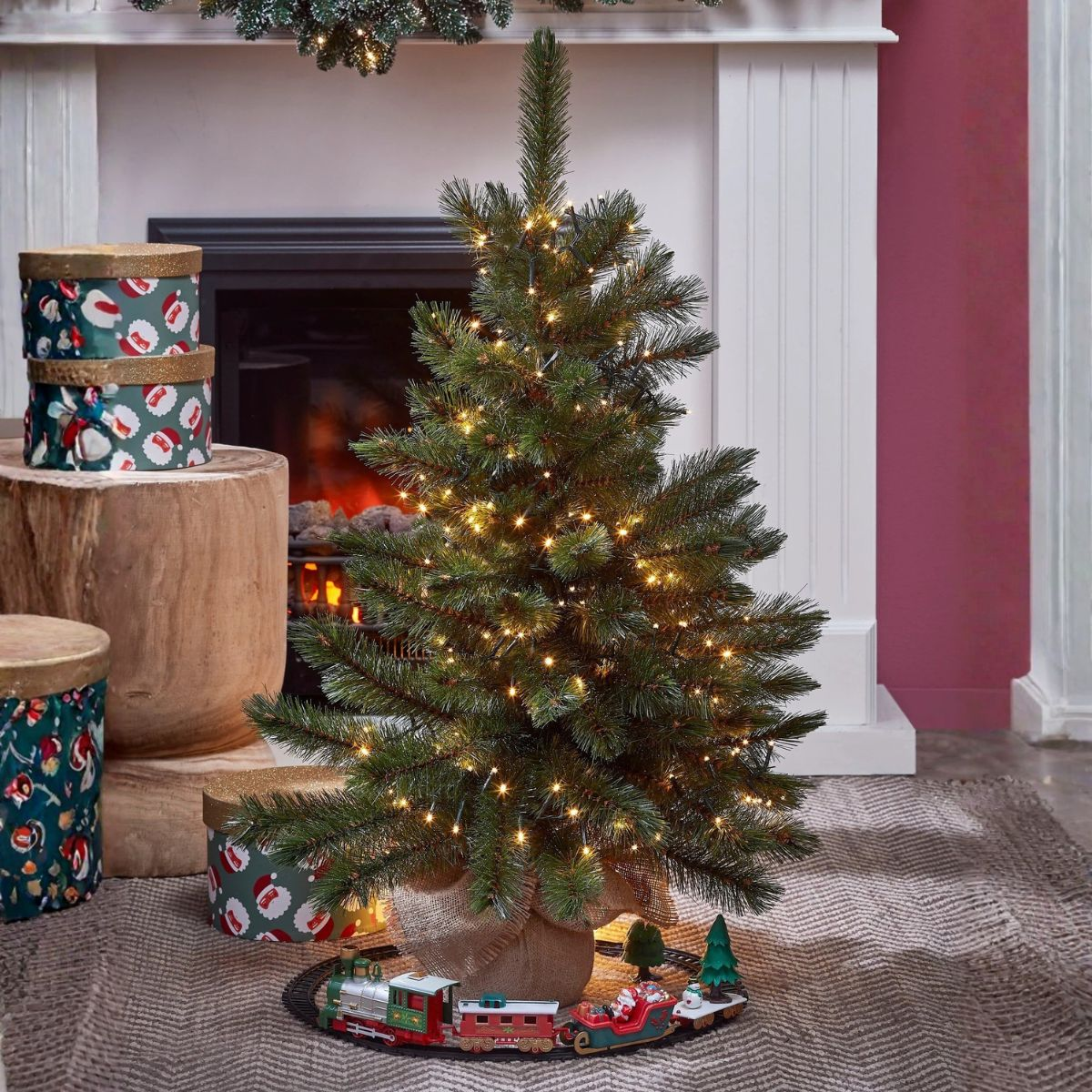 A decorated Christmas tree with lights, presents and a toy train at its base.