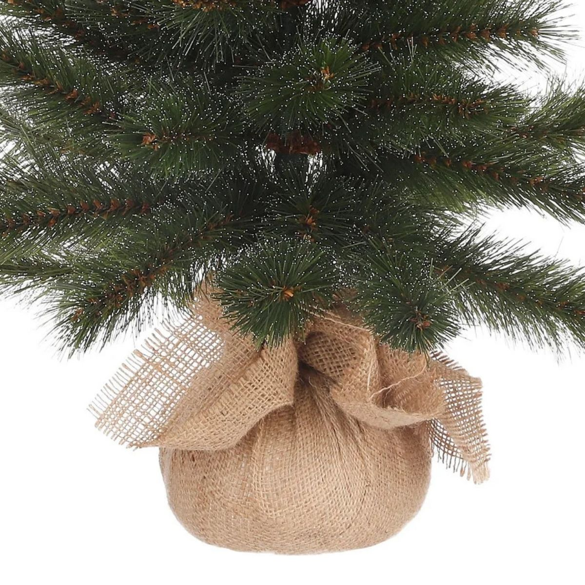 Gros plan d'un sapin de Noël artificiel aux aiguilles vert foncé et à base de sac en toile de jute.