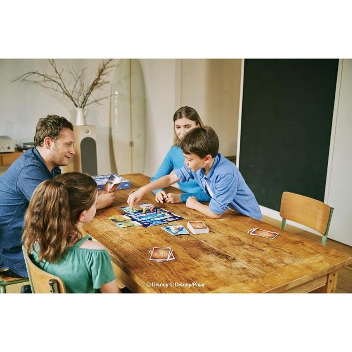 Familie spielt Brettspiel am Holztisch, Kinder im Vordergrund.