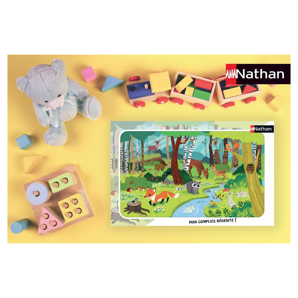 Ein Teddybär, Bauklötze, ein Spielzeugzug und ein Waldpuzzle auf gelbem Hintergrund.