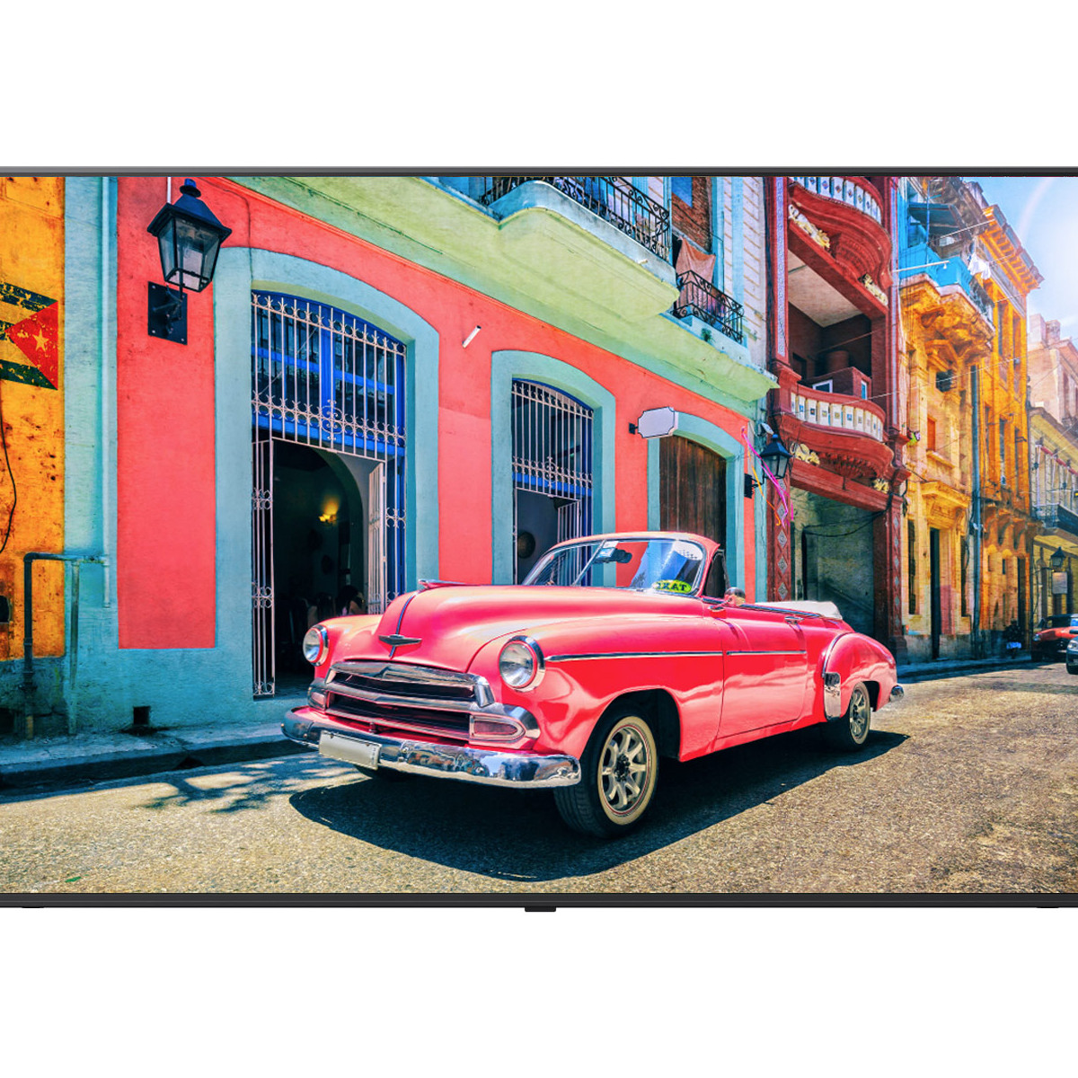 Un'auto cabriolet vintage rosa su una strada con edifici colorati.
