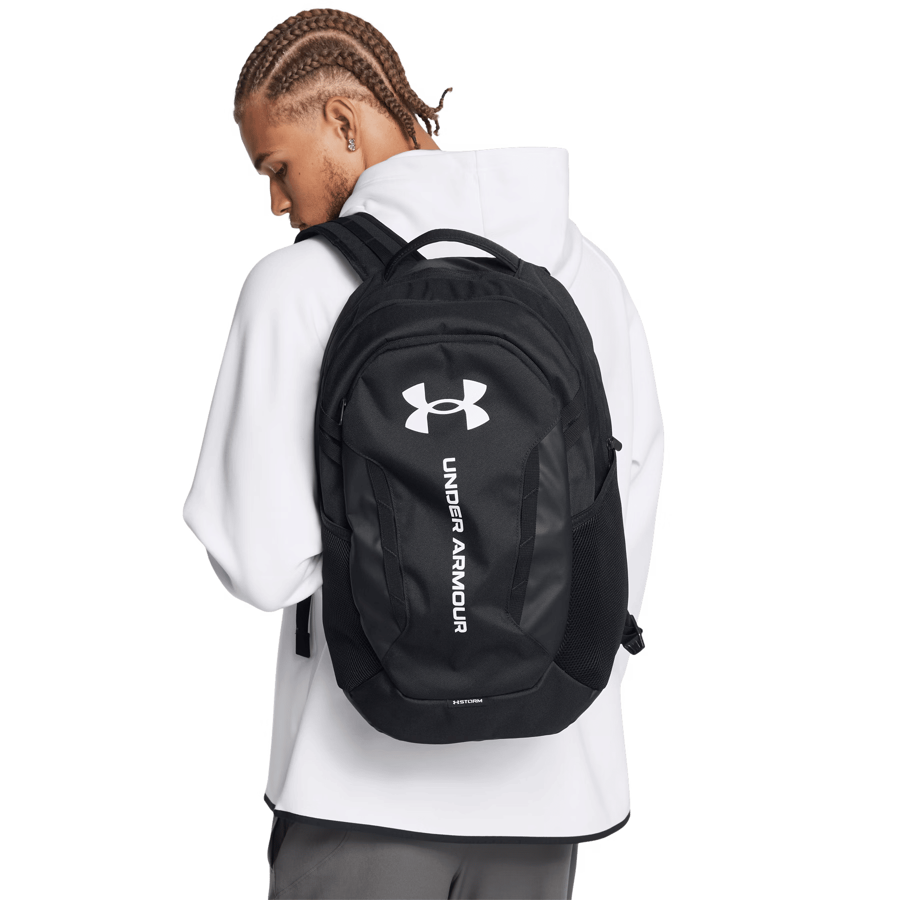 Ein Mann mit geflochtenen Haaren trägt einen schwarzen Rucksack mit weißem Logo.